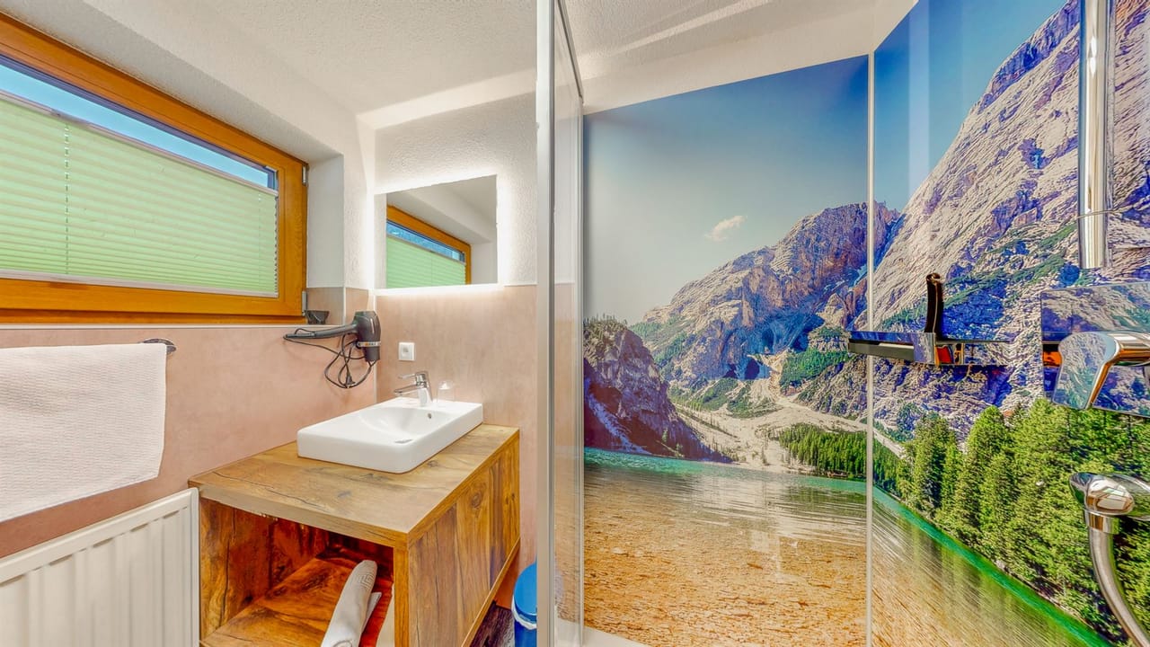Bad im Apartment Alpenruhe mit Bergsee-Duschwand und Lärchenholz-Waschtisch