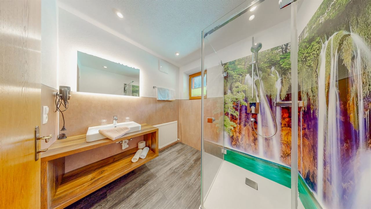 Bad im Apartment Gipfelglück mit Wasserfall-Duschwand und beleuchtetem Spiegel